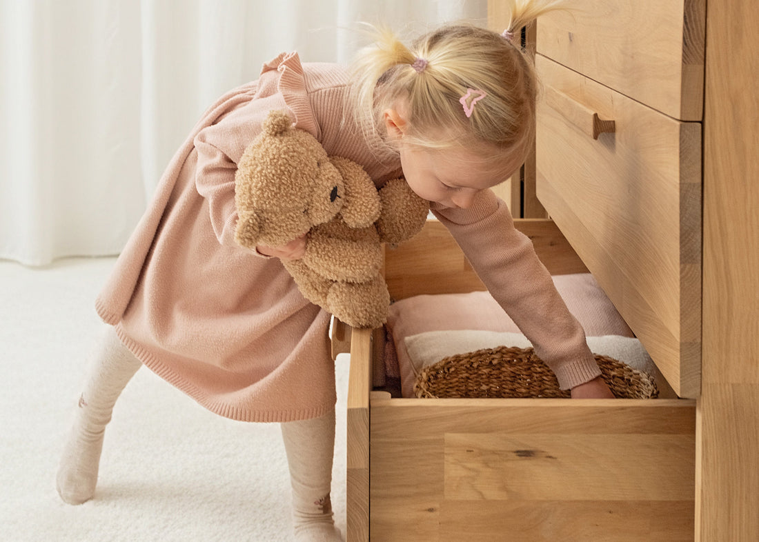 Ordnung im Kinderzimmer: Mädchen räumt Sachen in Kommode.
