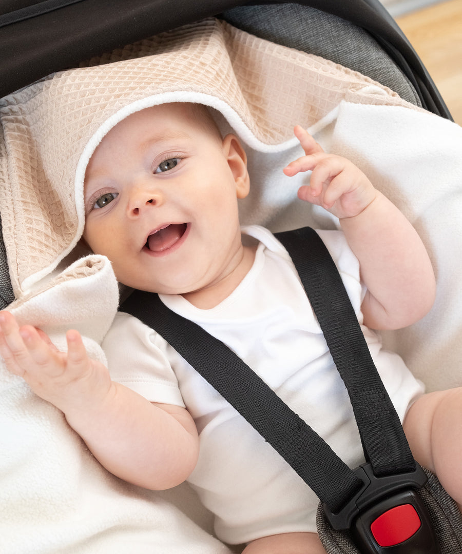 Wärmende Kapuze*Dank der wärmenden Kapuze ist das Köpfchen deines Babys unterwegs optimal geschützt bei Wind und Kälte.|Baby mit Einschlagdecke und Kapuze in Babyschale.