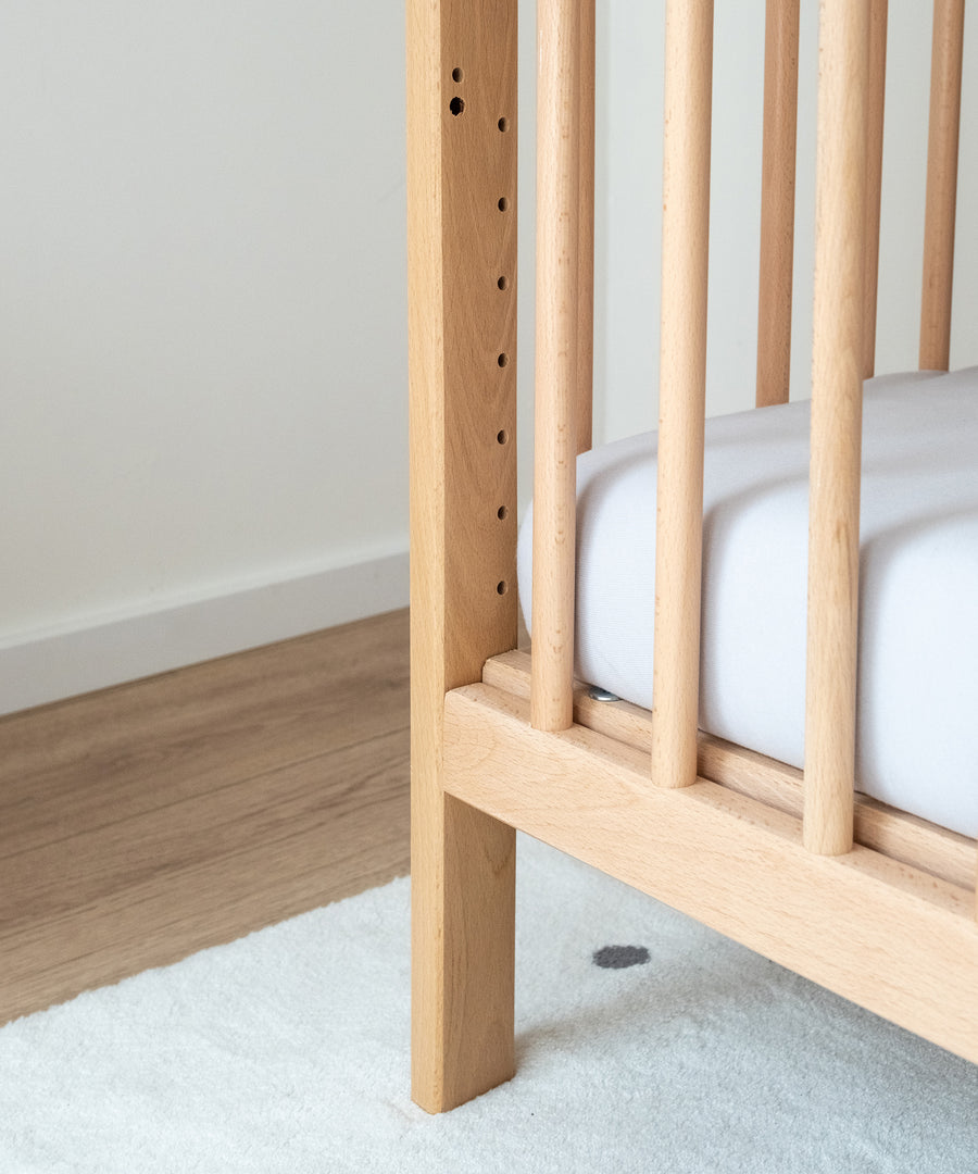 Hochwertige Materialien & FSC®-zertifiziert*Das Gitterbett wird aus massivem Buchenholz gefertigt und ausschließlich mit kinderfreundlichen Lacken behandelt.|Nahaufnahme Babybett Natur.