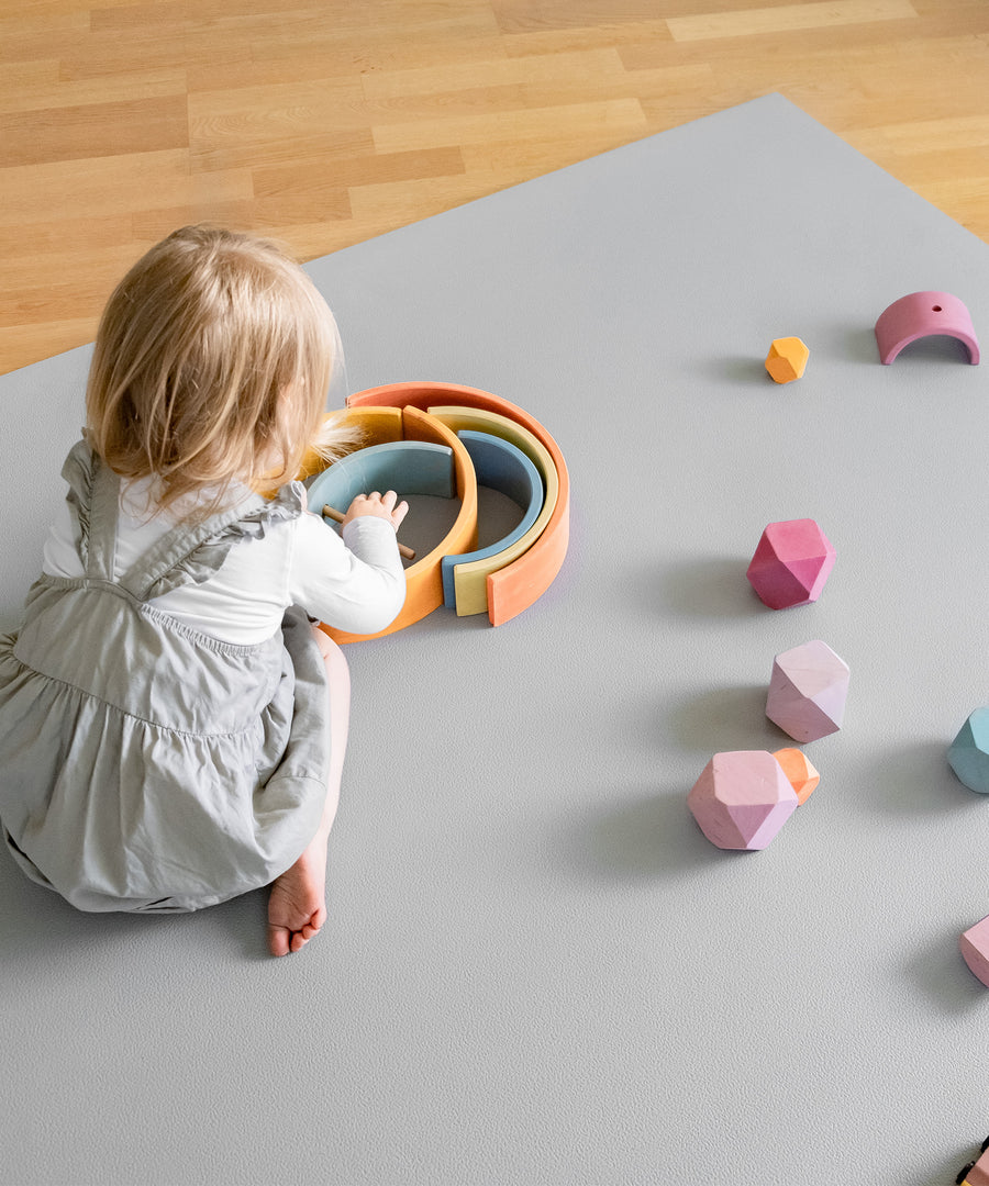 Rutschfest & standfest*Die Krabbelmatte PRO ist die ideale Spielunterlage. Sie ist weich und robust- optimal auch für Babys zum Krabbeln. Krabbelmatte in Hellgrau.|Kind spielt mit Holzspielzeug auf Krabbelmatte PRO.