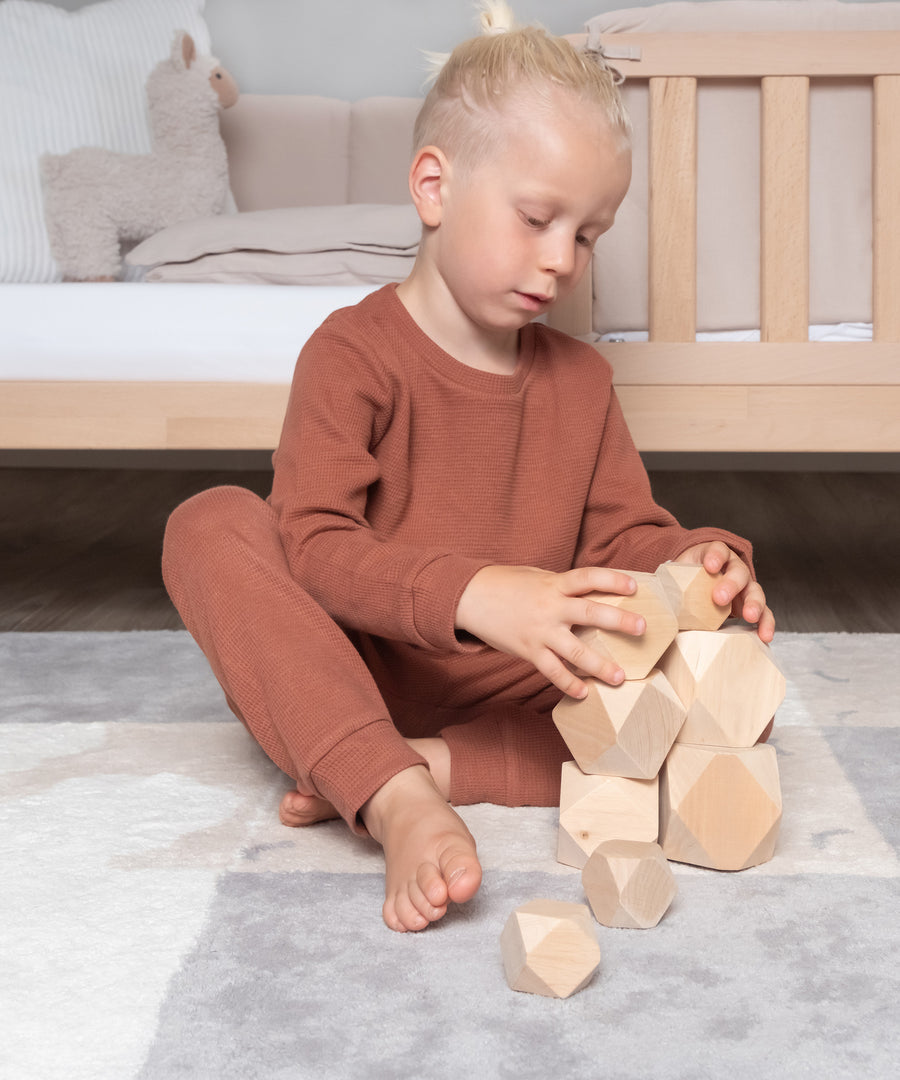 Einfach zum Wohlfühlen*Zum Schlafen oder einfach bequem zu Hause - der Schlafanzug ist hautfreundlich, atmungsaktiv und temperaturausgleichend.|Junge mit Kinder Pyjama spielt mit Balanciersteinen.