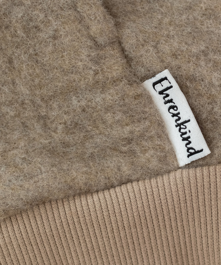 Hochwertig & nachhaltig*Unsere Wollfleece-Jacke wird aus feinster, mulesingfreier Bio-Merinowolle und zertifizierten Materialien in Europa hergestellt.|Nahaufnahme Wollfleecestoff Jacke Beige.