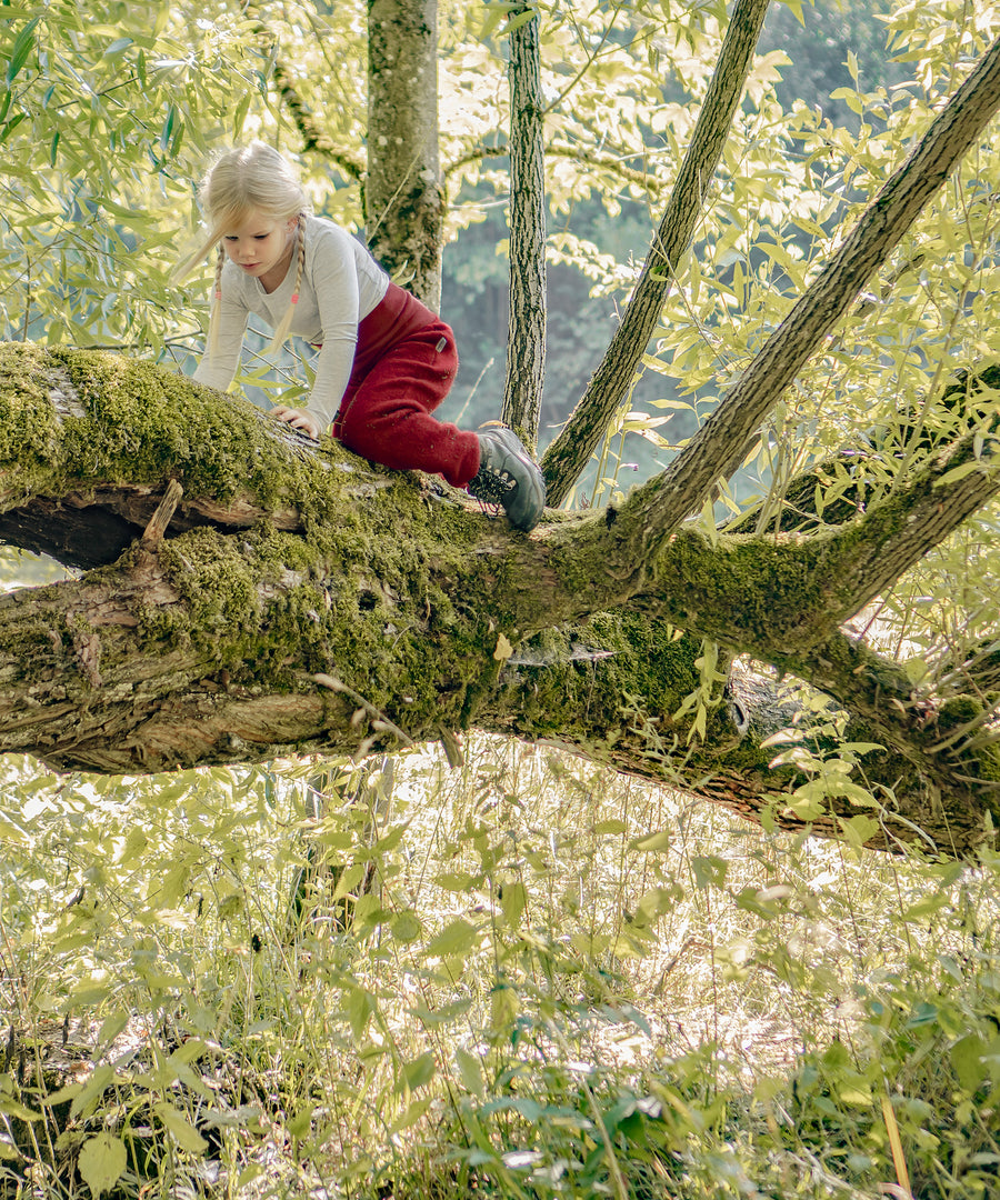 Reinschlüpfen & los geht’s*Dein Kind wird auch mit mehreren Lagen darunter in seiner Bewegungsfreiheit nicht eingeschränkt - perfekt zum Klettern und Toben.|Kind klettert auf einem Baum.