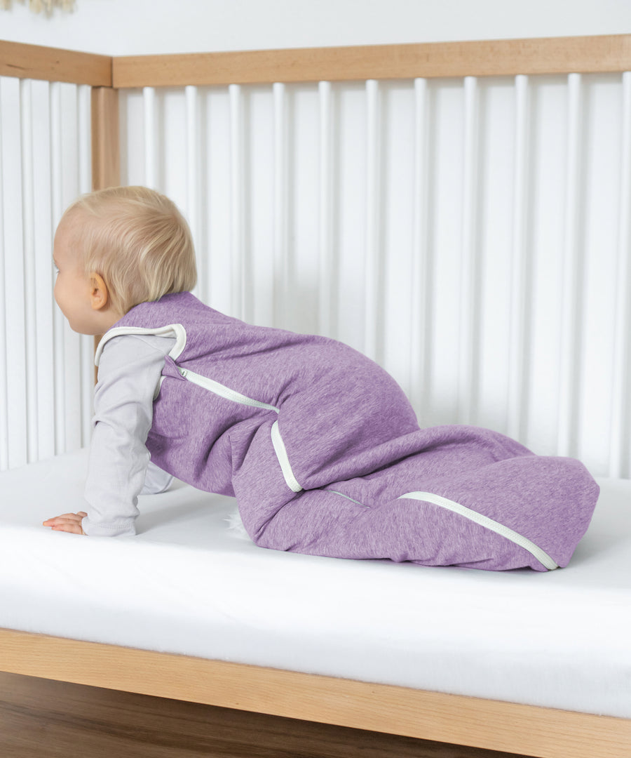 Baby trägt den weich wattierten Schlafsack aus Bio-Baumwolle.