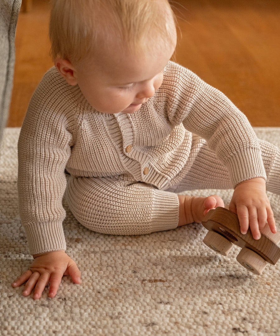 Bequemer Sitz*Rippbündchen an Armen und Beinen sorgen für guten Halt, ohne einzuengen - perfekt zum Spielen, Schlafen und für unterwegs.|Baby spielt im Strickoverall aus Bio-Baumwolle.