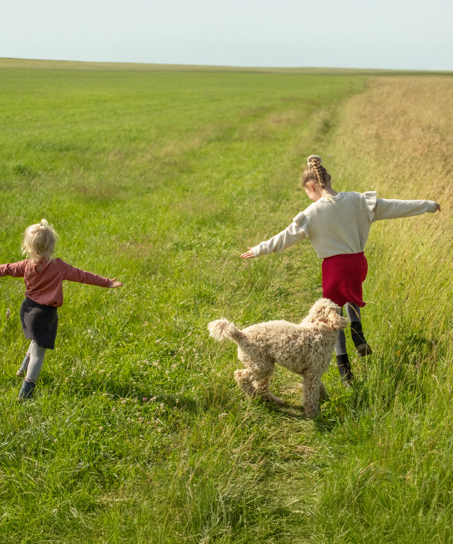 Kinder spielen in der Natur und tragen den Walkrock.
