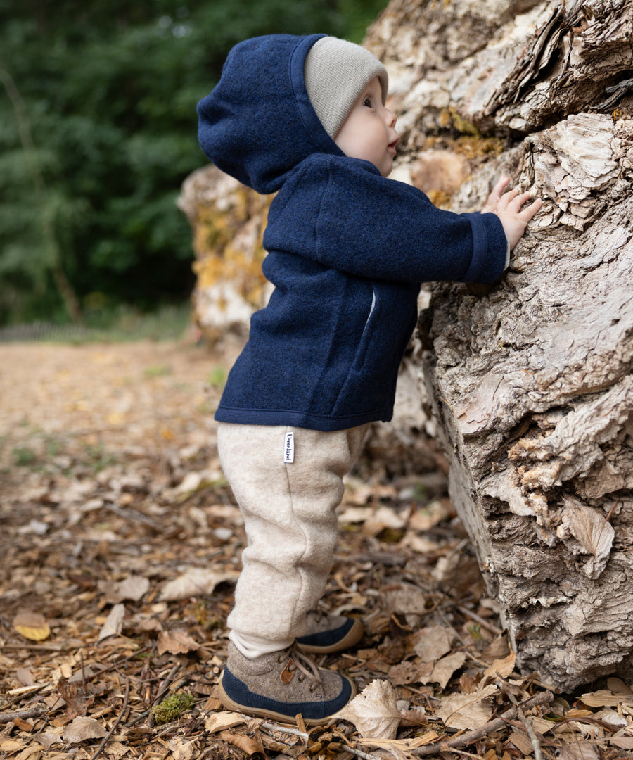 Mix & Match*Für zauberhafte Herbst-Looks: Die Lauflernschuhe sind farblich abgestimmt auf unsere Walk-Bekleidung und Woll-Accessoires.| Kind trägt Lauflernschuhe und die passende Walkjacke in Dunkelblau und dazu die Walkhose in Natur.