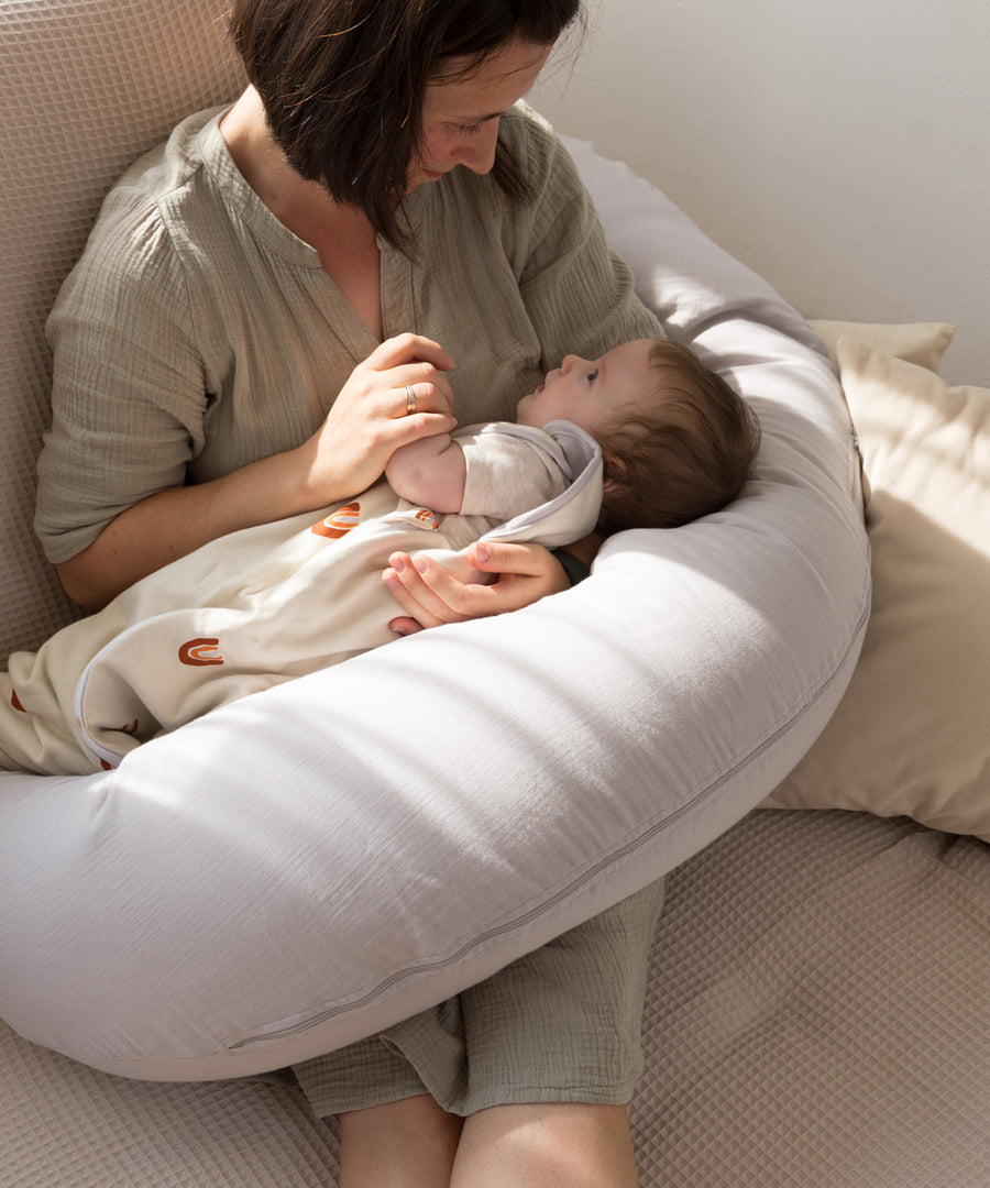Für innige Stillmomente*Die Füllung aus Mikroperlen passt sich jeder Stillposition flexibel an und entlastet Arme & Rücken auch während langer Stillphasen.|Mutter stillt ihr Baby auf dem Stillkissen.