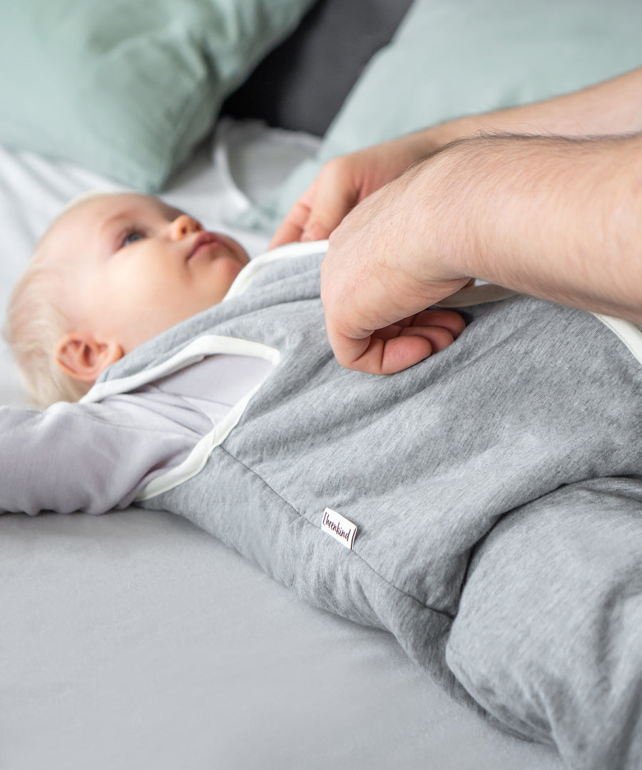 Weich wattiert*Der Ganzjahresschlafsack mit TOG 2.0 ist mit einer leichten, wärmenden Wollwattierung ausgestattet.| Kind trägt Schlafsack grau.