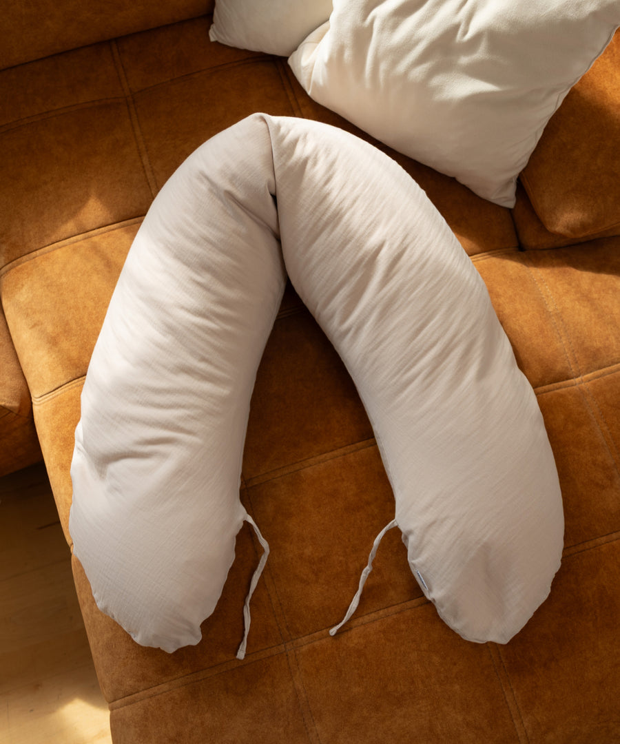 Flexibel und geräuschlos formbar*Das Stillkissen mit Mikroperlen lässt sich geräuschlos formen und unterstützt dich und dein Baby optimal.| Stillkissen liegt auf dem Sofa.