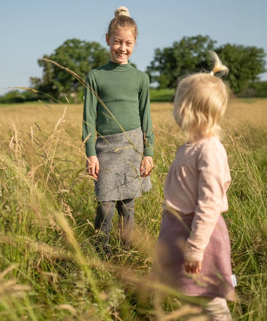 Weich und zuverlässig warm*Wärmender Materialmix: Der Walkrock aus Bio-Schurwolle und Bio-Baumwolle ist ein treuer Begleiter - drinnen wie draußen.|Kinder tragen den Walkrock.