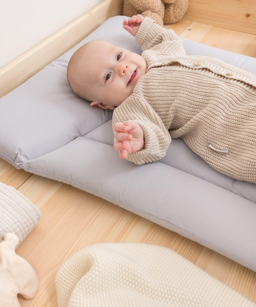 Baby liegt auf Wickelauflage beim Wickeln auf der Kommode