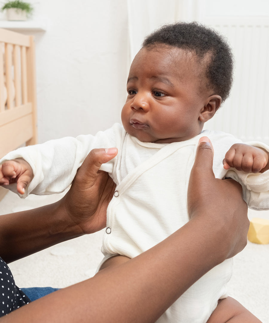 Selbstreinigende Wirkung*Wolle nimmt kaum Gerüche auf - Bakterien haften schlecht an, Gerüche werden reduziert. Daher ist kein häufiges Waschen nötig.|Baby wird von Mama gehalten.