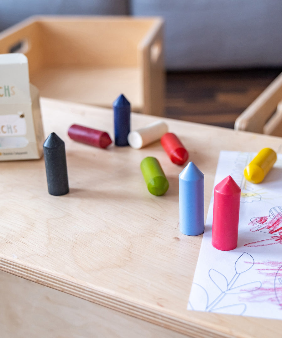 Wachsmalstifte in verschiedenen Farben liegen auf dem Tisch.